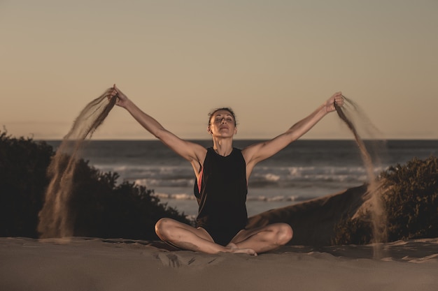 Retrato de uma mulher fazendo yoga na praia