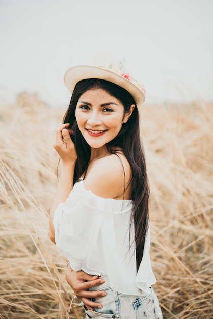 Retrato de uma mulher feliz asiática sorridente no estilo retrô do filtro de imagem do campo de trigo