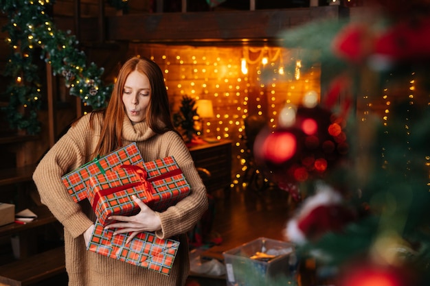 Retrato de uma mulher feliz e surpreendida soltando caixas de presentes com presentes de Natal embrulhados em papel artesanal