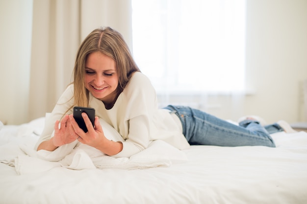 Retrato de uma mulher feliz em suas mensagens de texto adorável quarto
