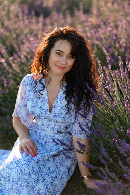 Retrato de uma mulher feliz em um vestido azul, aproveitando um dia ensolarado de verão em um campo de lavanda Ar fresco Estilo de vida