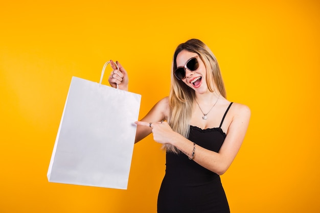 Retrato de uma mulher feliz, mostrando sacolas de compras na venda de sexta-feira negra. Ofertas da Shopp.
