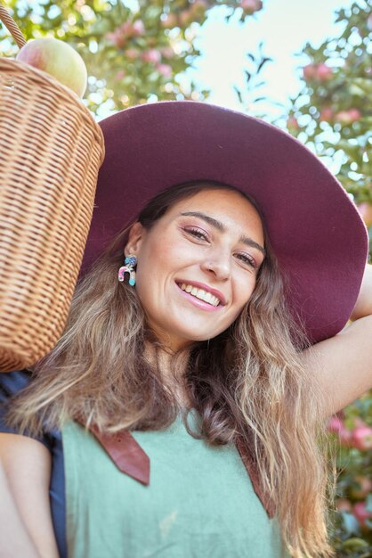 Retrato de uma mulher feliz segurando uma cesta de maçãs frescas colhidas de árvores na fazenda de pomar sustentável lá fora em dia ensolarado Rosto de agricultor alegre colhendo frutas orgânicas suculentas na estação para comer