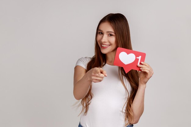 Foto retrato de uma mulher feliz segurando uma forma de coração contra um fundo branco
