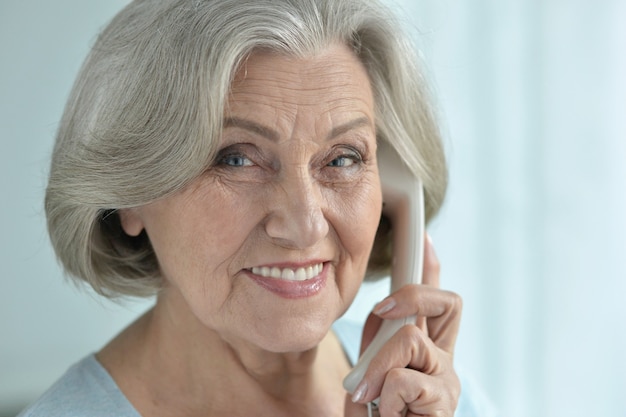 Retrato de uma mulher feliz sênior falando ao telefone