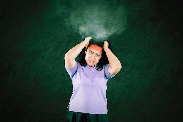 Foto retrato de uma mulher gorda descontente com dor de cabeça e sua cabeça queimando contra um fundo escuro