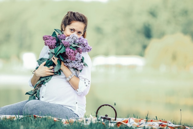 Retrato de uma mulher grávida feliz com um buquê de lilases em uma foto