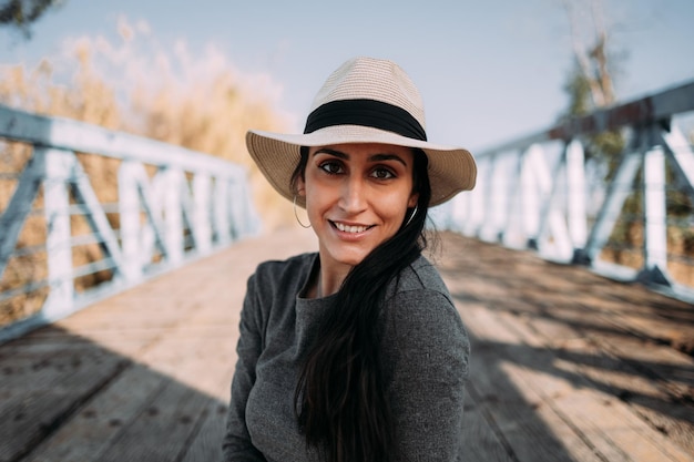 Retrato de uma mulher hispânica sorridente com chapéu sentado olhando para a câmera