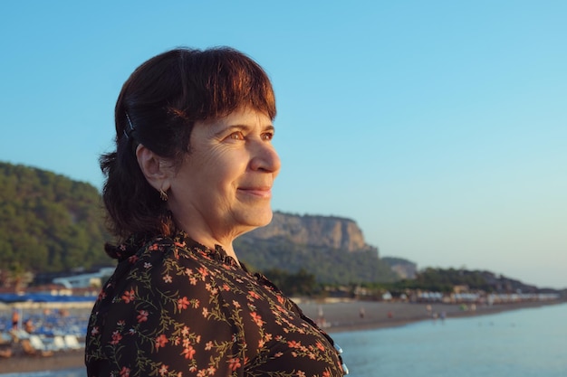 Retrato de uma mulher idosa na praia à luz do sol nascente