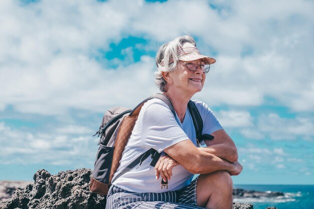 Foto retrato de uma mulher idosa sentada ao ar livre de frente para o mar olhando para o horizonte desfrutando da natureza