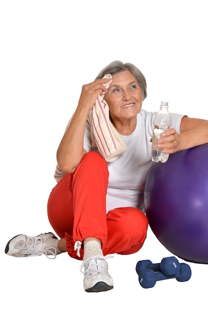 Foto retrato de uma mulher idosa sentada no chão com água depois de se exercitar isolado no branco