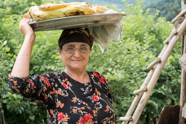 Foto retrato de uma mulher idosa sorridente carregando comida na cabeça