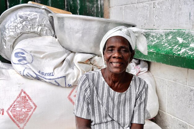 Retrato de uma mulher idosa sorridente sentada junto à parede