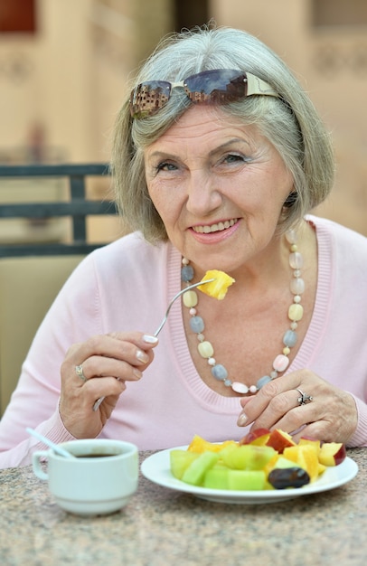 Retrato de uma mulher idosa tomando café da manhã do lado de fora