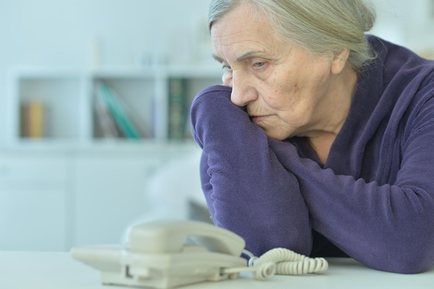 Foto retrato de uma mulher idosa triste olhando para o telefone