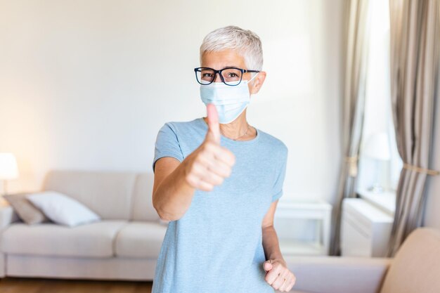 Foto retrato de uma mulher idosa usando uma máscara de proteção facial para prevenir o coronavírus e a névoa de fumaça retrato de um homem idoso usando uma máscaras faciais polegar para cima
