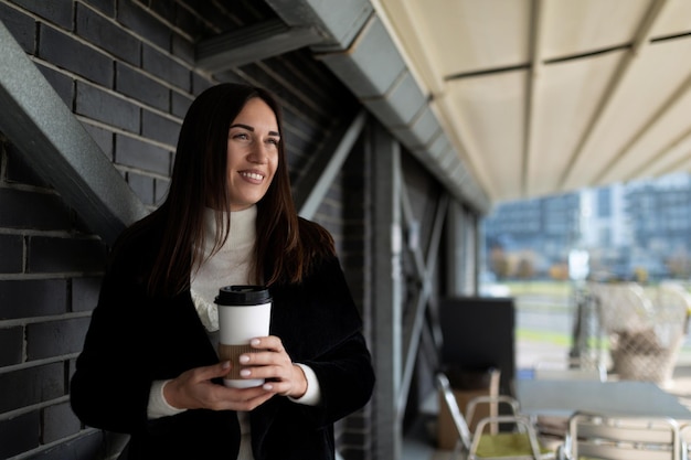 Retrato de uma mulher independente de negócios bem-sucedida com um sorriso no rosto com uma xícara de café em