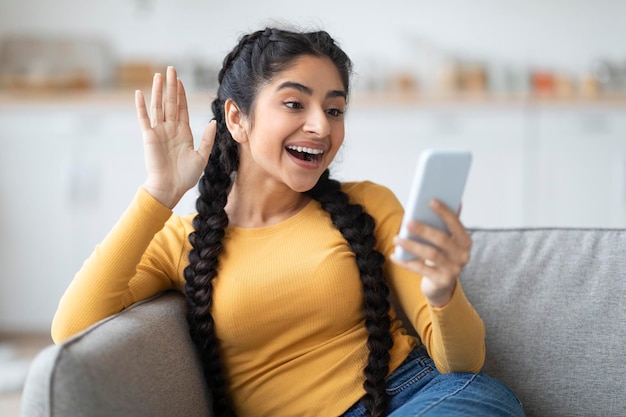 Retrato de uma mulher indiana feliz fazendo videochamada via smartphone em casa