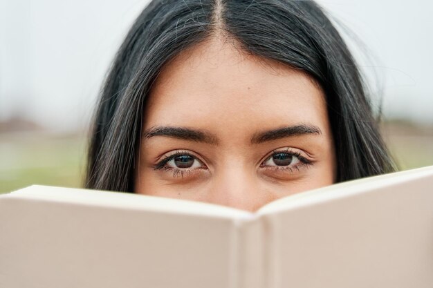 Retrato de uma mulher latina com um livro cobrindo o rosto