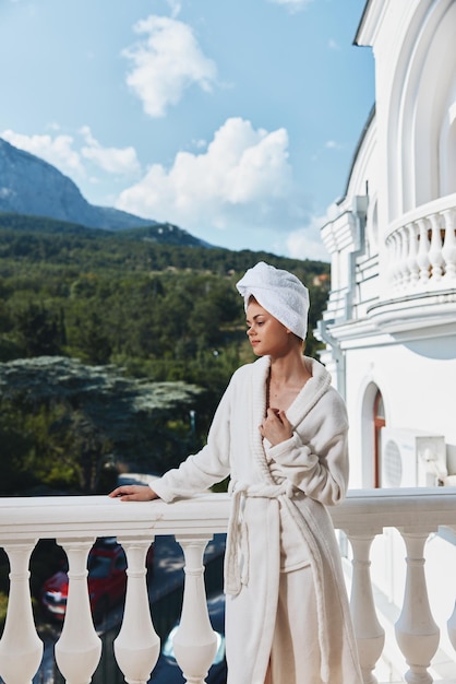 Retrato de uma mulher linda com uma toalha na cabeça em um roupão de banho branco ficando na varanda de um hotel conceito de relaxamento foto de alta qualidade