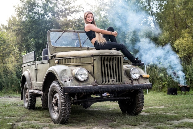 Retrato de uma mulher linda de cabelos longos sentada no capô do carro