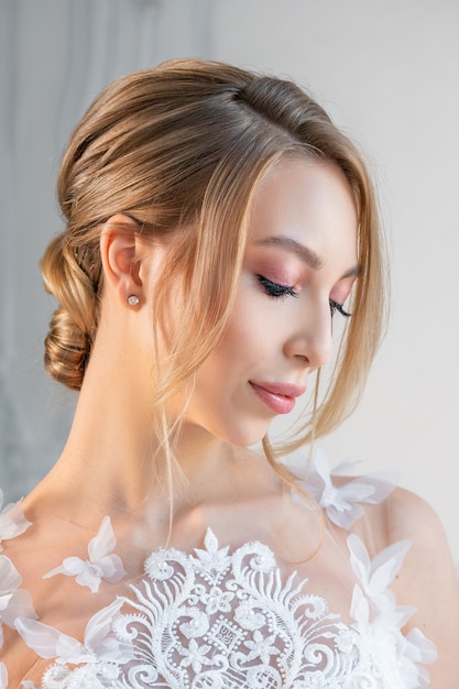 Retrato de uma mulher linda em um vestido de noiva branco com uma bela maquiagem e penteado