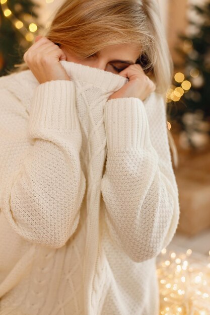 Foto retrato de uma mulher loira cobrindo o rosto com um suéter branco