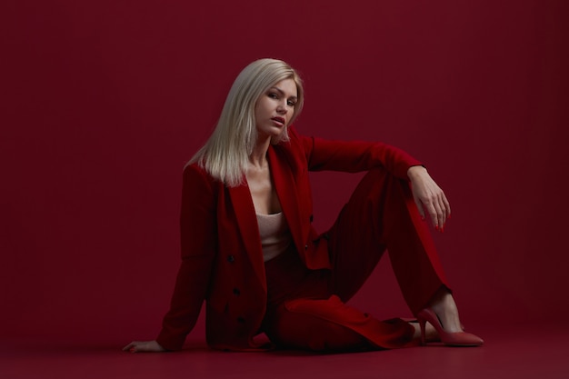 Retrato de uma mulher loira com um vestido vermelho sobre um fundo vermelho