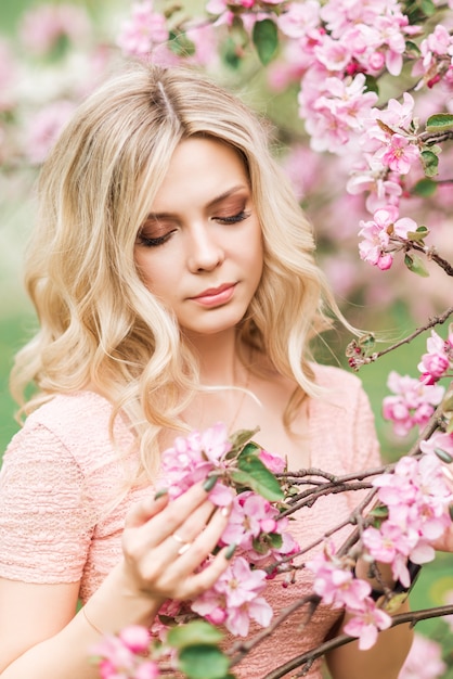 Retrato de uma mulher loira de flores cor de rosa. jardim primavera