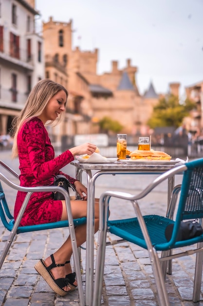 Retrato de uma mulher loira tomando café da manhã ao lado de um castelo medieval no verão