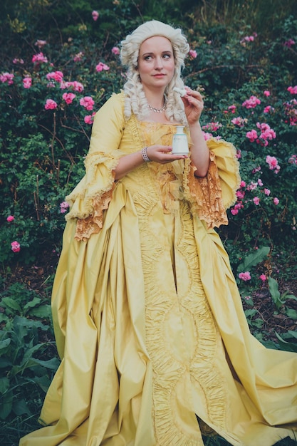 Retrato de uma mulher loira vestida com roupas barrocas históricas com penteado à moda antiga ao ar livre