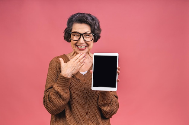 Foto retrato de uma mulher madura de idade avançada com a avó do computador tablet mostrando a tela do tablet