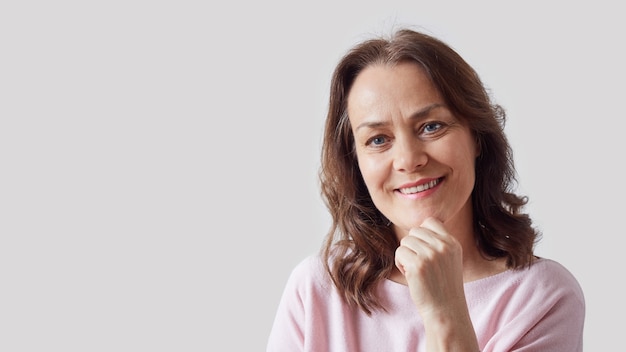 Retrato de uma mulher madura e bonita com um suéter rosa