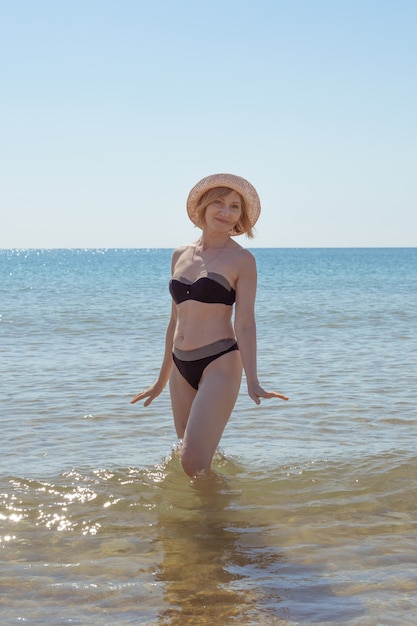 Retrato de uma mulher madura em um maiô e um chapéu para o mar. Viagens e férias no mar.