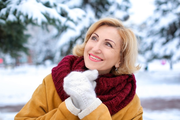 Retrato de uma mulher madura feliz em um parque nevado nas férias de inverno