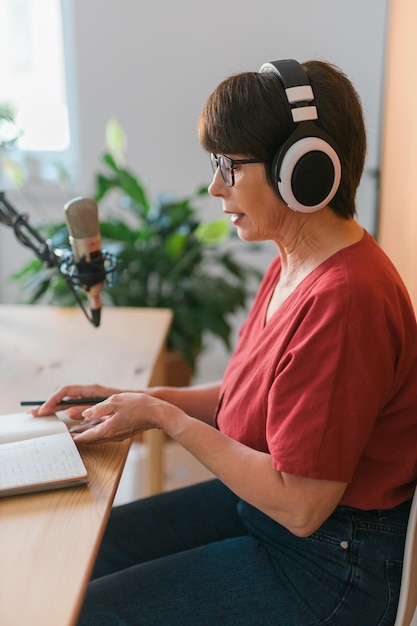 Retrato de uma mulher madura usando fones de ouvido e falando no podcast da estação de rádio online e