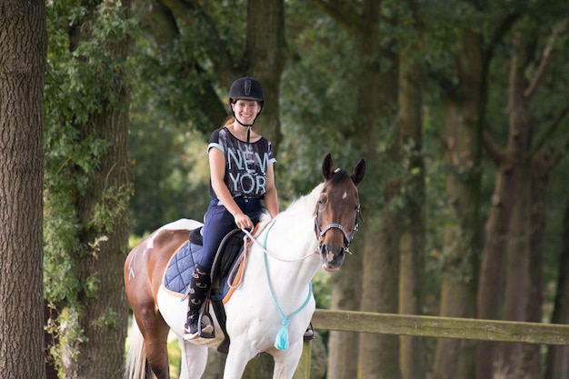 Retrato de uma mulher montando um cavalo contra árvores