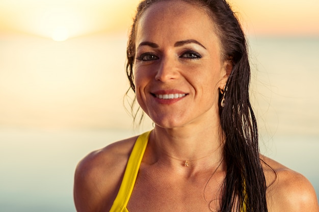 Retrato de uma mulher morena bronzeada em biquíni perto da piscina