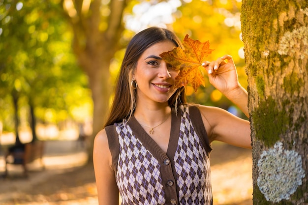 Retrato de uma mulher morena caucasiana no outono em um parque natural com uma folha no rosto