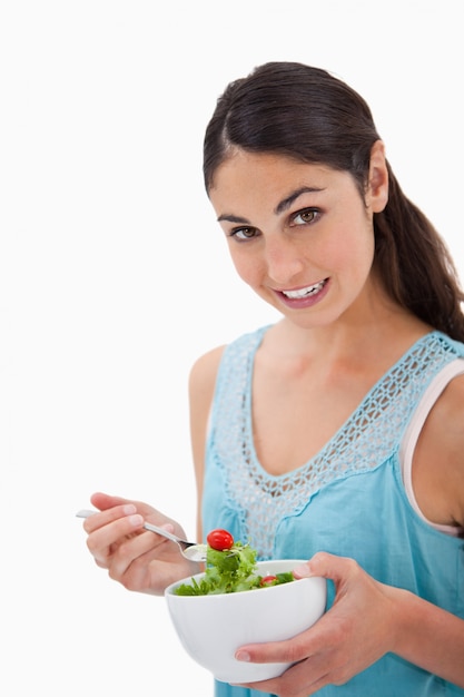 Retrato de uma mulher morena comendo uma salada