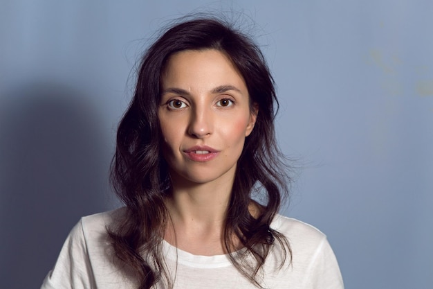 Retrato de uma mulher morena em uma camiseta de fundo azul