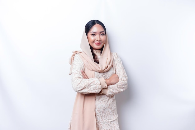 Retrato de uma mulher muçulmana asiática sorridente confiante usando hijab em pé com os braços cruzados e olhando para a câmera isolada sobre fundo branco