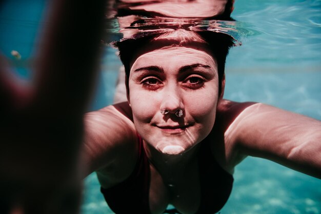 Foto retrato de uma mulher nadando debaixo d'água em uma piscina