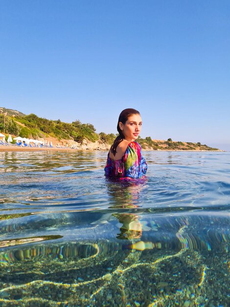 Foto retrato de uma mulher nadando no mar contra um céu claro