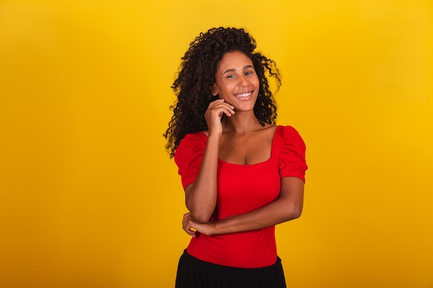 Retrato de uma mulher negra de raça mista, com grande cabelo afro, cabelos cacheados em fundo amarelo.