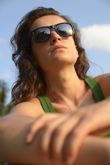 Foto retrato de uma mulher pensativa em óculos de sol. ela esta na praia