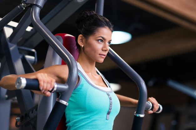 Retrato de uma mulher praticando esportes em uma máquina de exercícios na academia