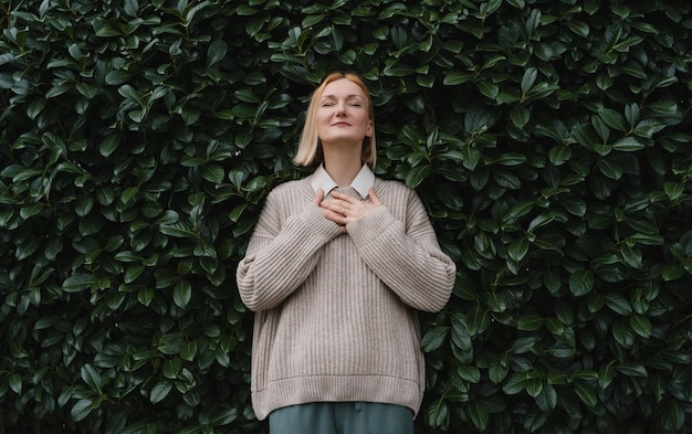 Retrato de uma mulher relaxada com os olhos fechados no fundo da parede de folhas verdes Conceito de fora do escritório WorkLifeBalance Fazendo uma pausa Zen e equilibrando as pessoas Estabilidade através da saúde mental