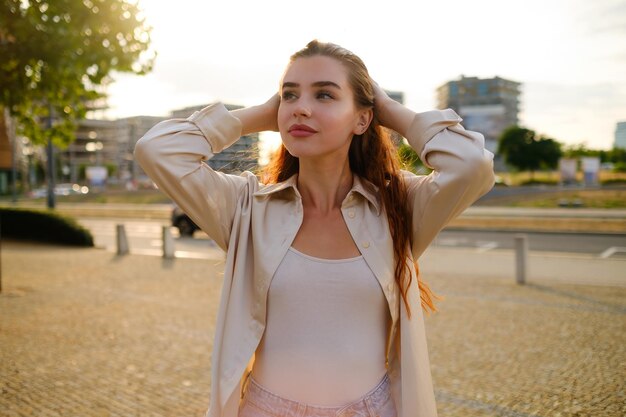 Foto retrato de uma mulher ruiva segurando a cabeça enquanto estava de pé na rua