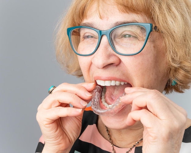 Foto retrato de uma mulher segurando aparelhos dentários
